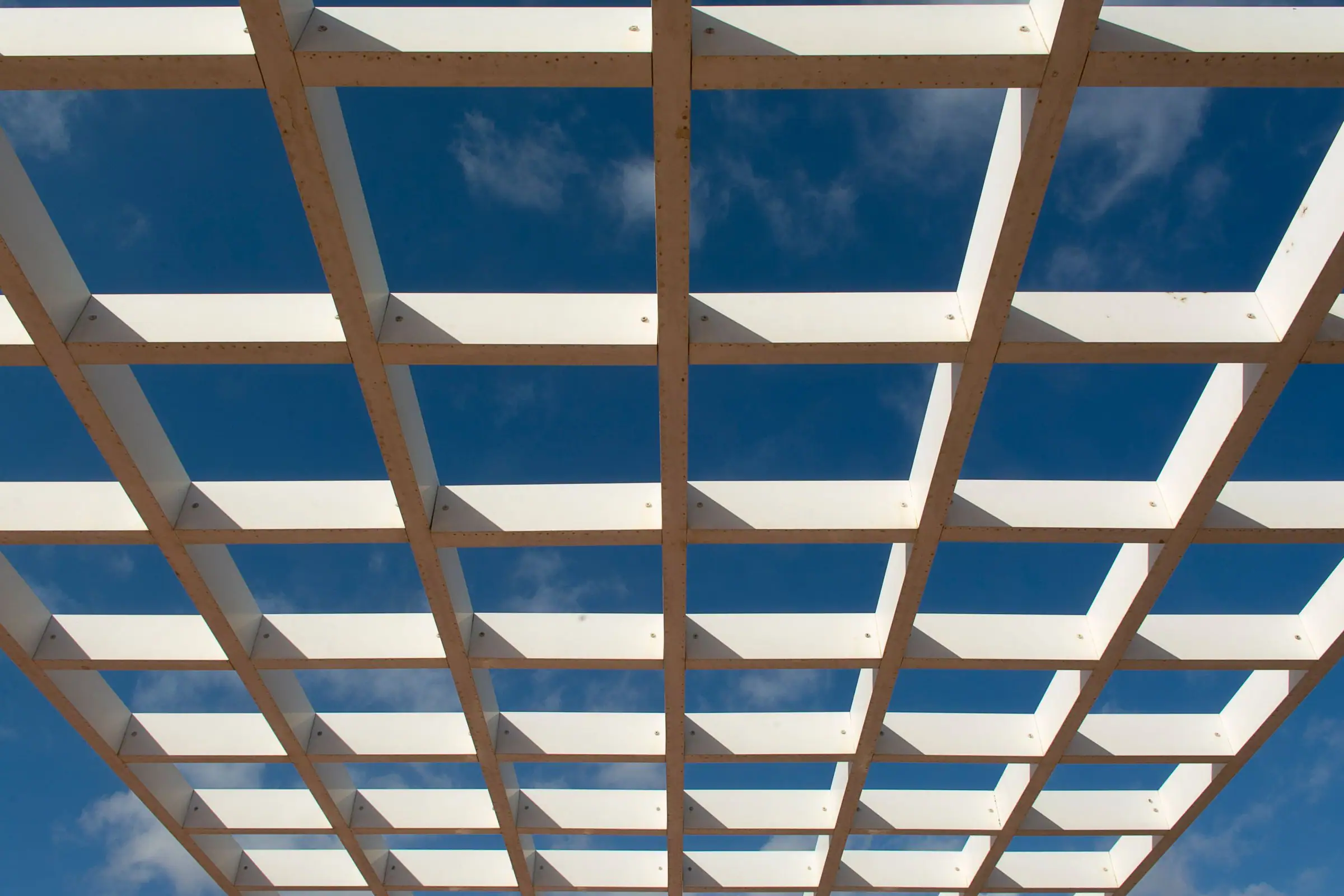 Wood lattice shade grid seen from below against a blue sky
