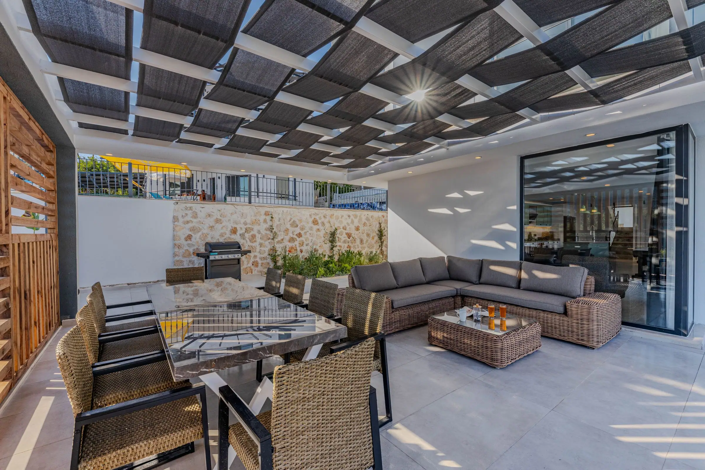 Patio under a slatted roof with dining and lounge furniture