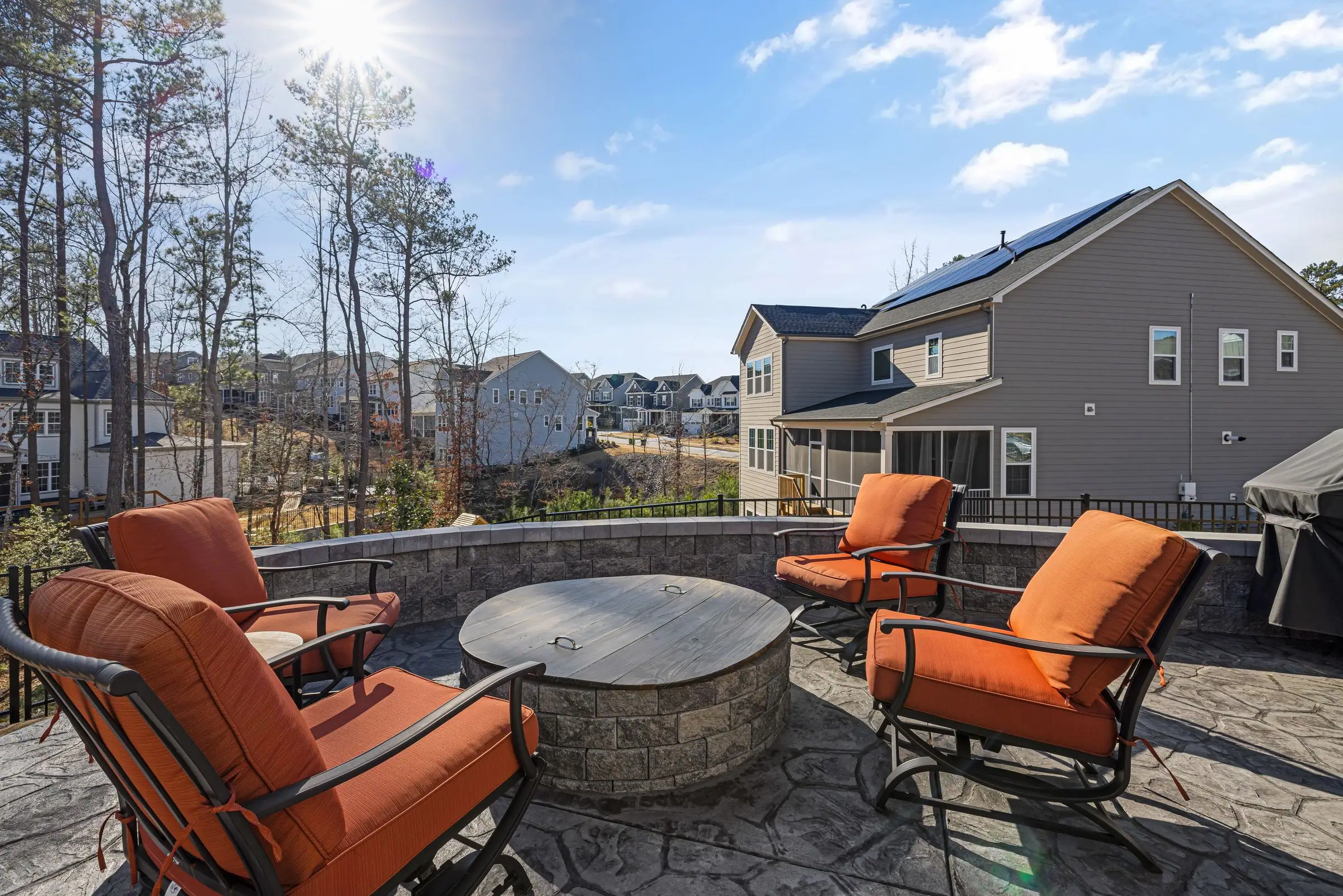 Stone patio with a fire pit and orange cushioned chairs